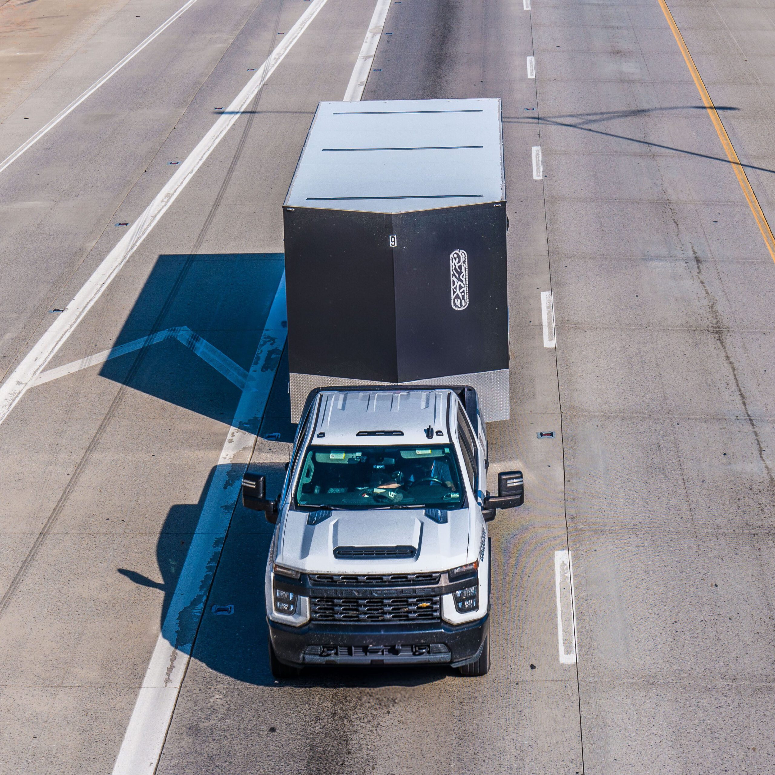 Pickup truck towing enclosed trailer on road